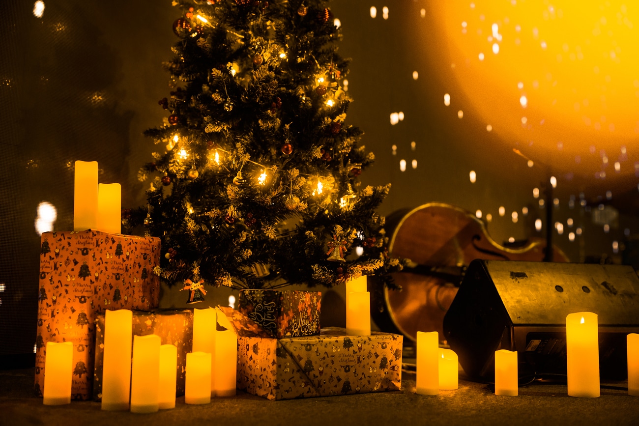 Un árbol de navidad con un violonchelo, velas encendidas y regalos envueltos